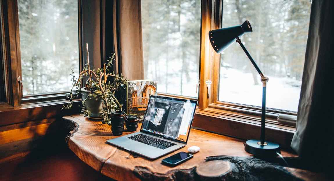 Werkplek bij een raam in het late licht, de laptop staat nog aan